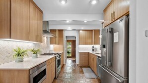 Una cocina moderna con armarios de madera, electrodomésticos de acero inoxidable y suelo de baldosas en patrón de espiga.