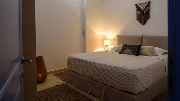 Une chambre à coucher avec un lit, une lampe de chevet et une décoration murale en macramé.