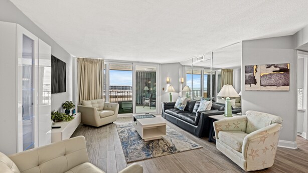 A modern living room with a sofa, armchairs, a coffee table, and a large window with a view. - Ocean View, recently updated, 24 hour security + Free Attraction Tickets! (Myrtle Beach)