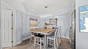 A dining area with a wooden table and chairs, a chandelier, and a patterned rug. - Ocean View, recently updated, 24 hour security + Free Attraction Tickets! (Myrtle Beach)