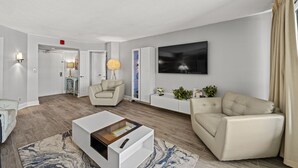 A modern living room with a sofa, a coffee table, and a TV mounted on the wall. - Ocean View, recently updated, 24 hour security + Free Attraction Tickets! (Myrtle Beach)