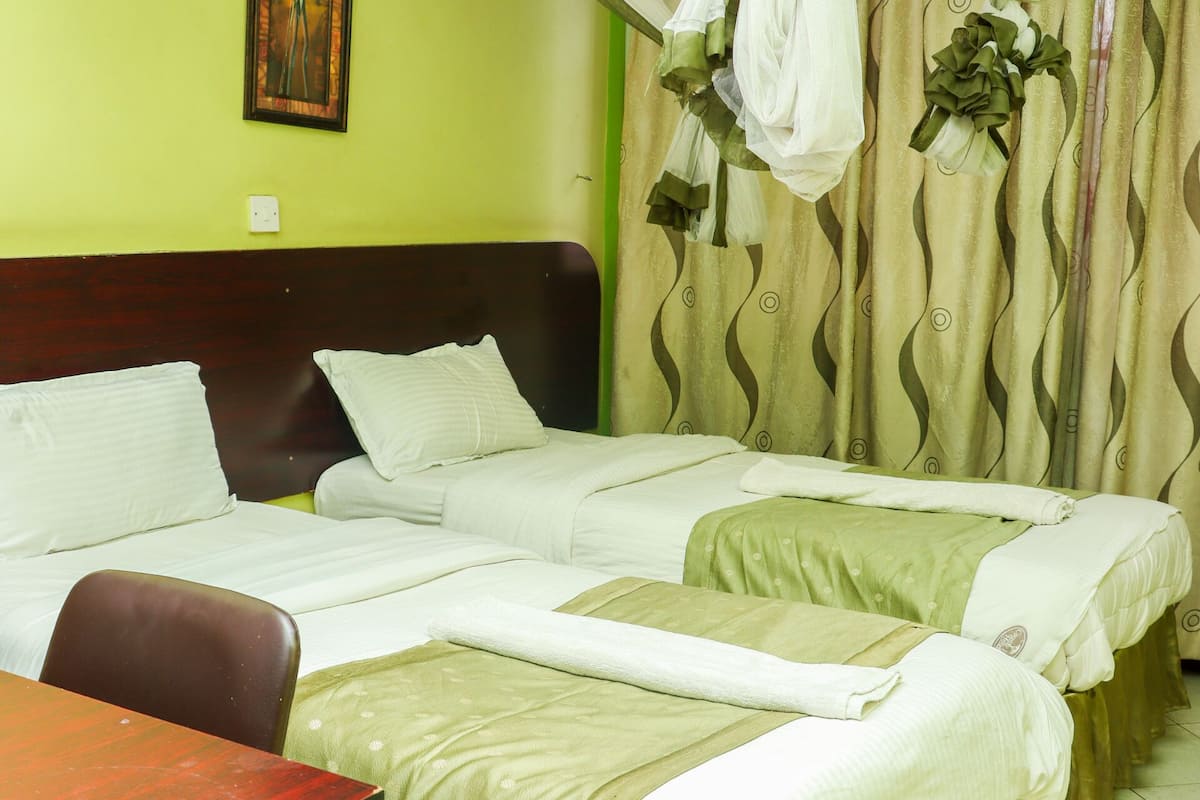 A hotel room with two beds, a wooden desk, and a painting on the wall.