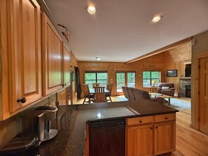 A wooden cabin interior with a kitchen, dining area, and living space.