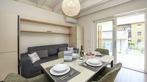 A modern dining area with a table set for four, a grey sofa, and a hanging light fixture.