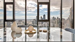 Une chambre située dans un immeuble de grande hauteur, avec une table en verre, des objets décoratifs et une vue sur la ville.