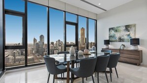 Un espace de restauration moderne avec vue sur la ville, une table en verre et des chaises grises.
