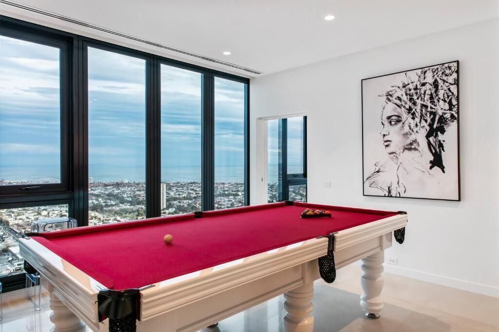 A pool table in a room with large windows offering a city view.