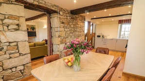 A dining area with a stone wall, wooden table, and chairs. - Lanshaw House (Lancaster)