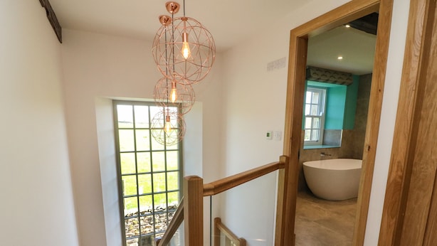 A staircase leading to a bathroom with a large bathtub and a modern light fixture. - Lanshaw House (Lancaster)