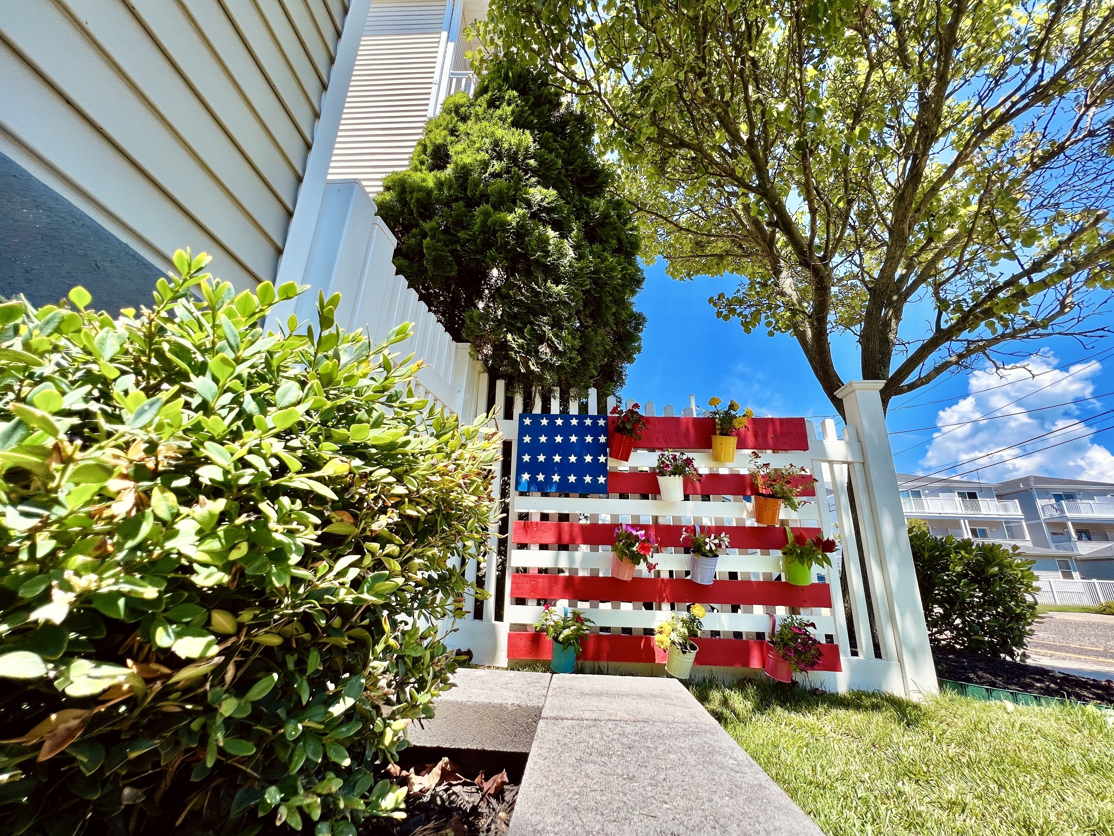 A building with a white fence decorated with an American flag and potted plants.