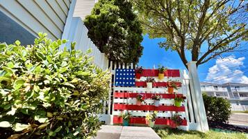 A building with a white fence decorated with an American flag and potted plants.