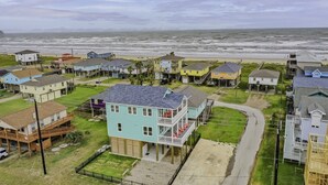 A coastal residential area with houses, a road, and a view of the ocean.