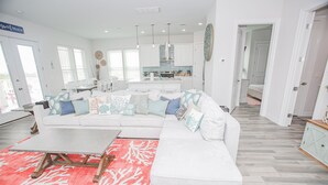 A spacious living room with a white sectional sofa, a coffee table, and a red patterned rug.