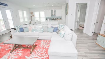 A spacious living room with a white sectional sofa, a coffee table, and a red patterned rug.