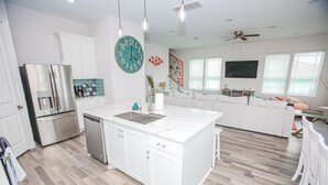 A spacious kitchen with white cabinetry, a stainless steel refrigerator, and a central island with a sink.
