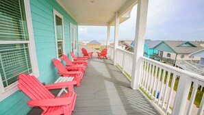 A porch with red Adirondack chairs and a view of neighboring houses.