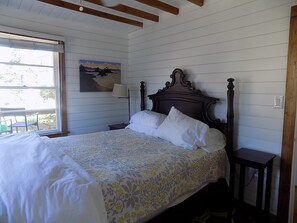 A neatly made bed with a floral bedspread, a wooden headboard, and a nightstand with a lamp. - Carolina Kiwi - Off-Ocean, 3-Bedrooms (Pawleys Island)