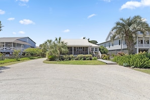 A two-story building with a covered porch, surrounded by a gravel driveway and lush landscaping.