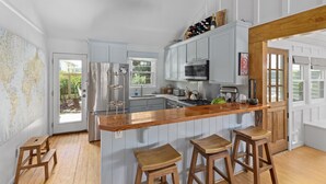 Una cocina con taburetes de madera, una isla grande, electrodomésticos de acero inoxidable y un mapa mundial en la pared.