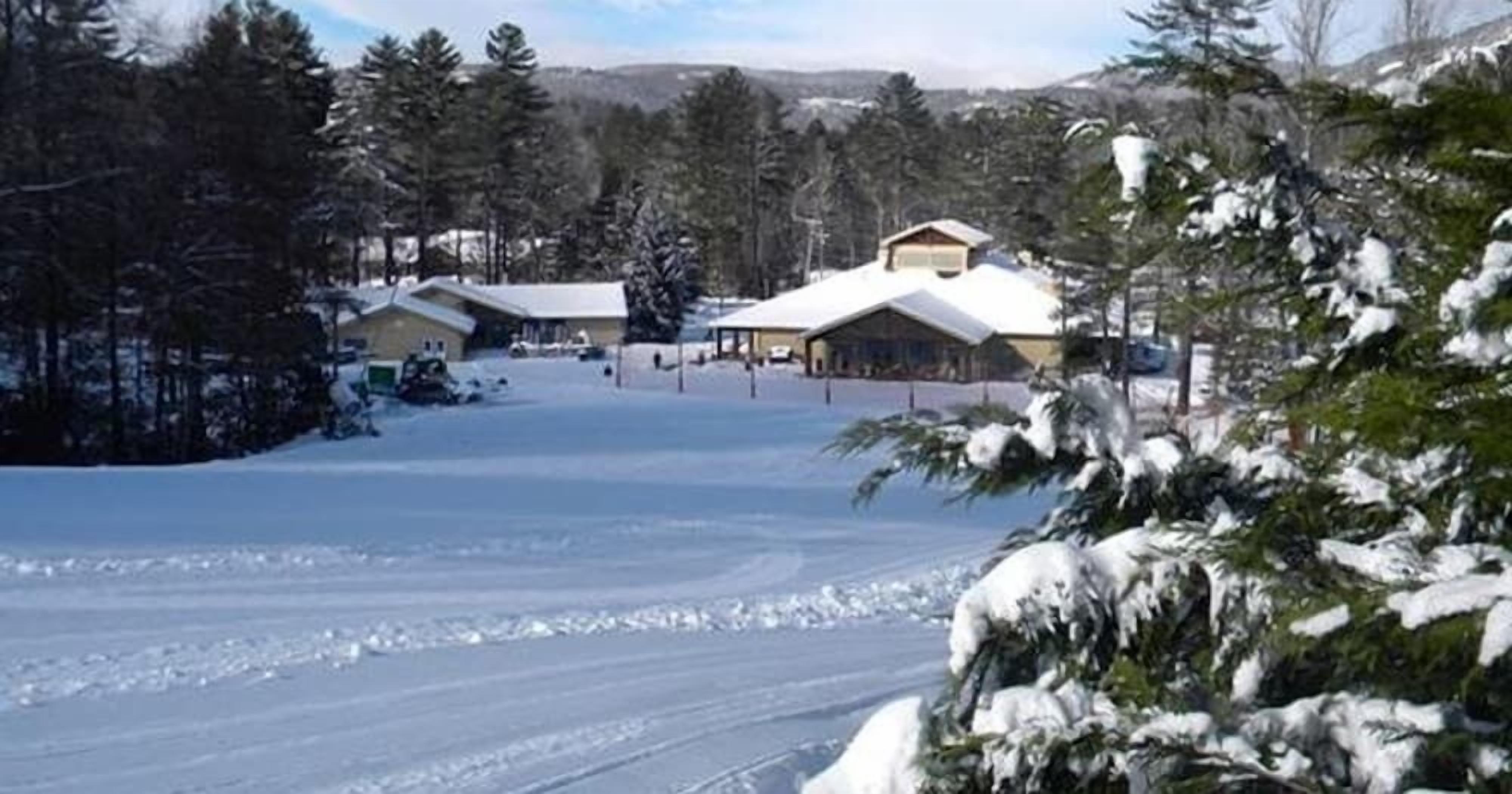 A snow-covered landscape with buildings, including a lodge with a snow-covered roof and a covered area.