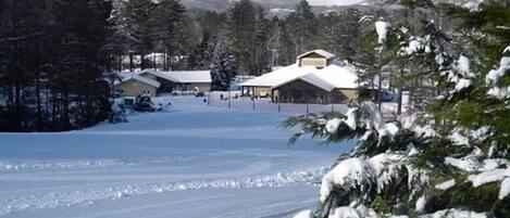 A snow-covered landscape with buildings, including a lodge with a snow-covered roof and a covered area.