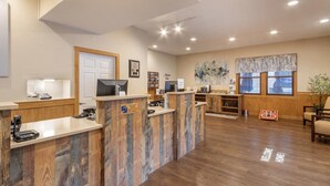 A reception area with a wooden reception desk, a coffee machine, a TV, and a 'Welcome Home' sign on the floor. - Fairway Forest Resort (Sapphire)