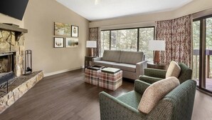 A living room with a stone fireplace, a sofa, a coffee table, and a TV. - Fairway Forest Resort (Sapphire)