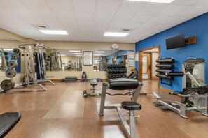 A gym with various exercise equipment, mirrors, and a blue wall. - Fairway Forest Resort (Sapphire)