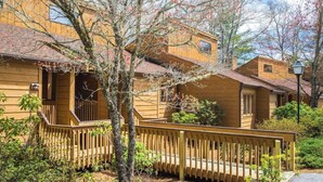 A wooden cabin with a porch, a small deck, and a street lamp. - Fairway Forest Resort (Sapphire)