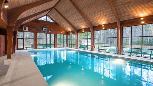 A large indoor swimming pool with wooden beams and large windows. - Fairway Forest Resort (Sapphire)
