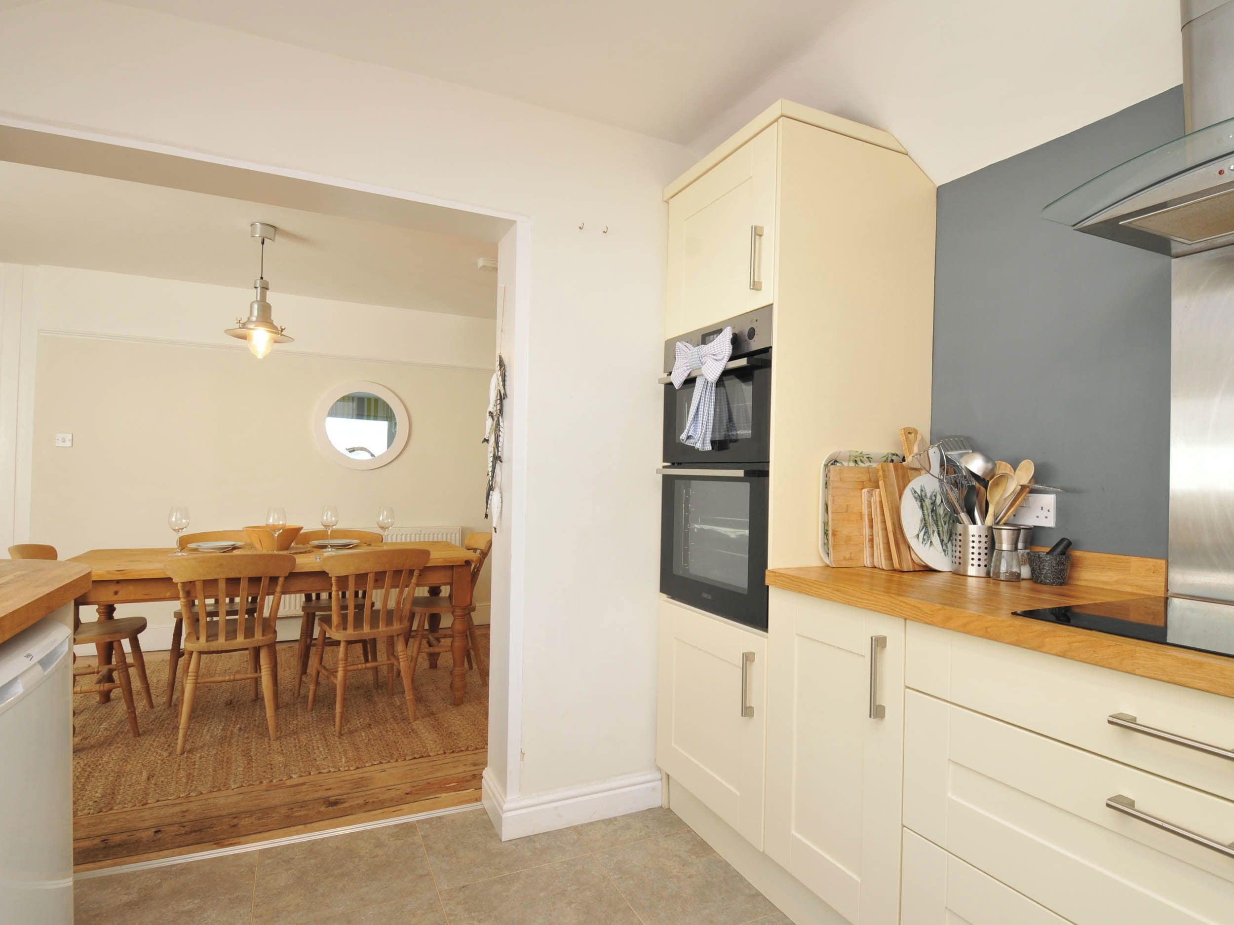 Una cocina con armarios de madera, una campana extractora de acero inoxidable y un comedor con mesa y sillas de madera.