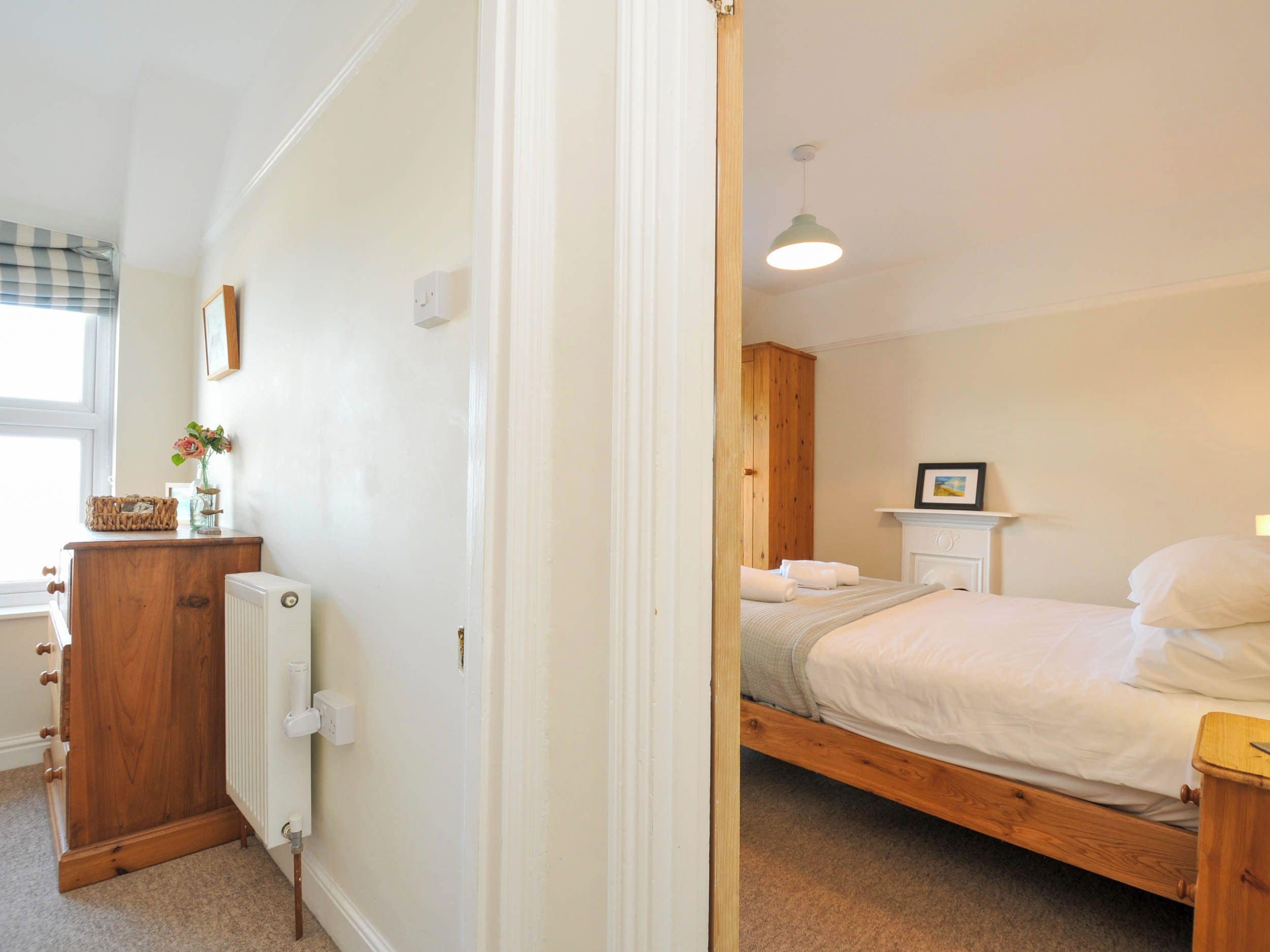 A bedroom with a wooden bed, a bedside table, a radiator, and a window with a view.