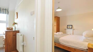 A bedroom with a wooden bed, a bedside table, a radiator, and a window with a view.