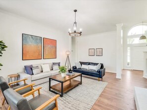 A spacious living room with a sofa, a coffee table, and a chandelier.