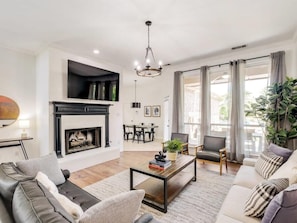 A modern living room with a fireplace, leather sofas, a coffee table, and a dining area with chairs.