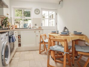 A kitchen with a washing machine, a sink, a window, and a table with chairs.
