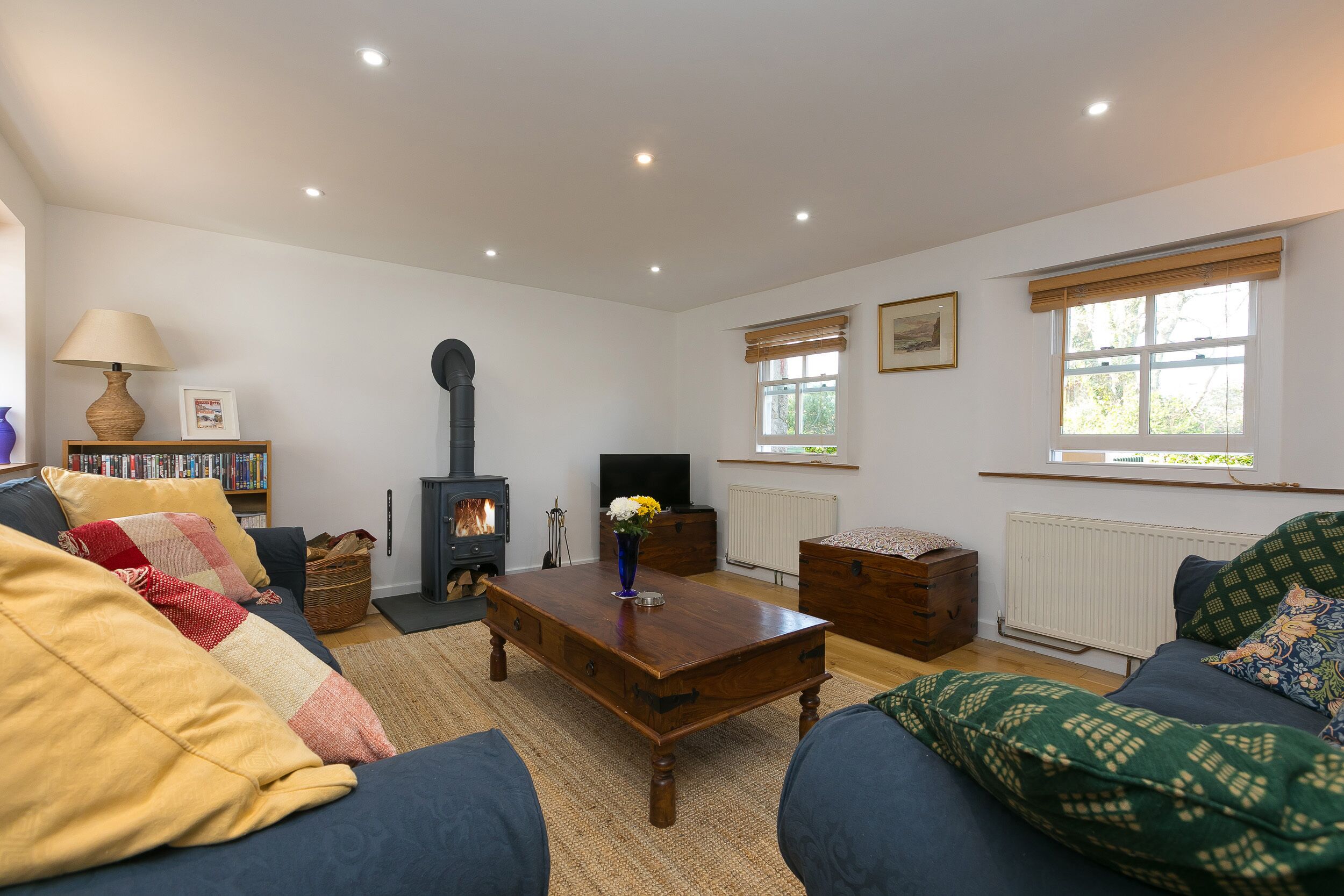 A cozy living room with a sofa, a wooden coffee table, a fireplace, and a bookshelf.