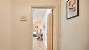 A hallway leading to a bedroom with a bed, a desk, and a chair. There is a framed picture on the wall and a sign indicating the room number. - Host & Stay | Studio Pod 2 (Saltburn-by-the-Sea)
