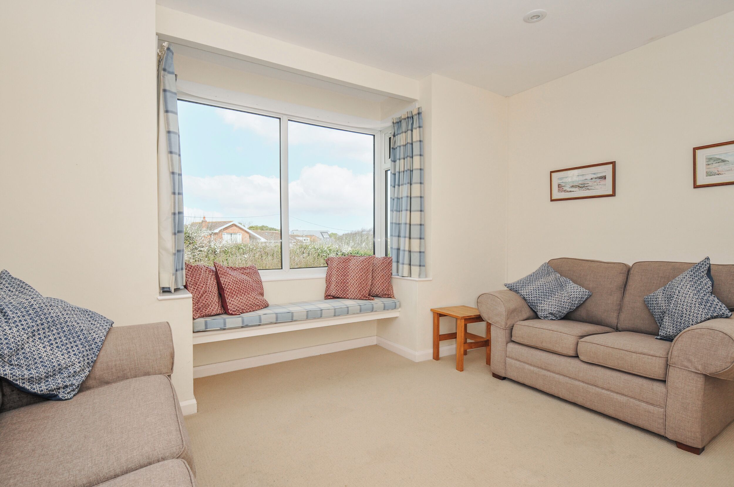 A living room with a sofa, a bench, a small table, and a window with curtains.