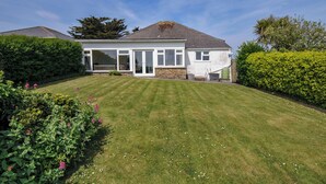 A two-story house with a large lawn, a conservatory, and a stone wall. - Hillcroft Bungalow (Wadebridge)