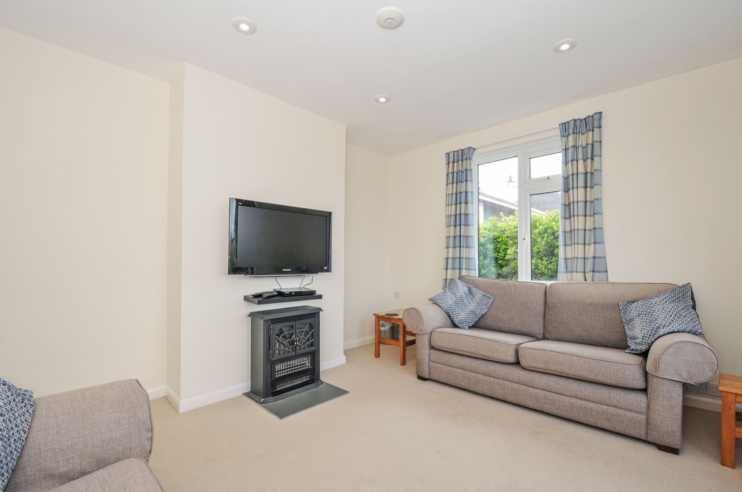 A living room with a sofa, a television, a fireplace, and a window with curtains.