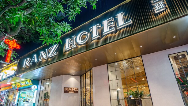 Exterior del hotel Ranz, con una fachada moderna, grandes ventanales y un llamativo letrero iluminado.
