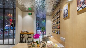 Un interior moderno con un mostrador de recepción de madera, taburetes de bar, un jarrón con flores y una pared decorada con cuadros.
