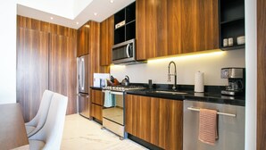 Una cocina moderna con armarios de madera, electrodomésticos de acero inoxidable y encimera negra.