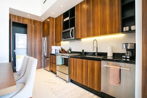 Eine moderne Küche mit Holzausstattung, Edelstahlgeräten und einer schwarzen Arbeitsplatte.
