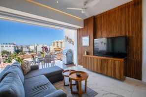 En moderne stue med et stort fjernsyn, en sofa og en balkon med havemøbler.