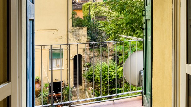 Ein Balkon mit Metallgeländer, Blick auf umliegende Gebäude und ein befestigter Boden.