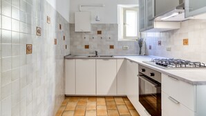 Eine kompakte Küche mit weißen Schränken, einem Gasherd und einem Fenster über der Spüle.
