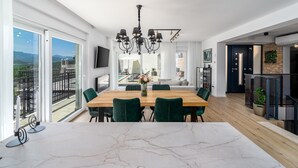 Een moderne eetruimte met een marmeren bar, een houten tafel en groene fauteuils.