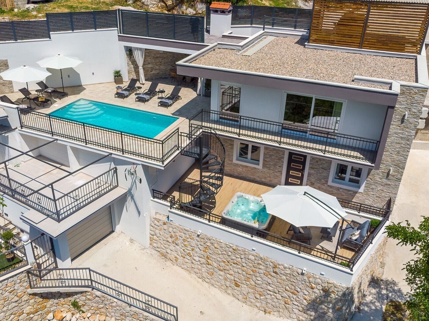 Et moderne hus med to etager, en pool på taget og en udendørs spa samt udendørs møbler.